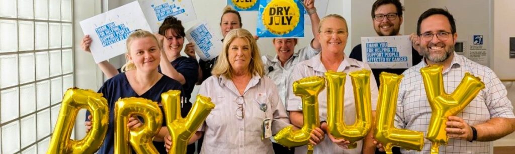 CCLHD staff promoting Dry July by holding posters and balloons that spell out dry july